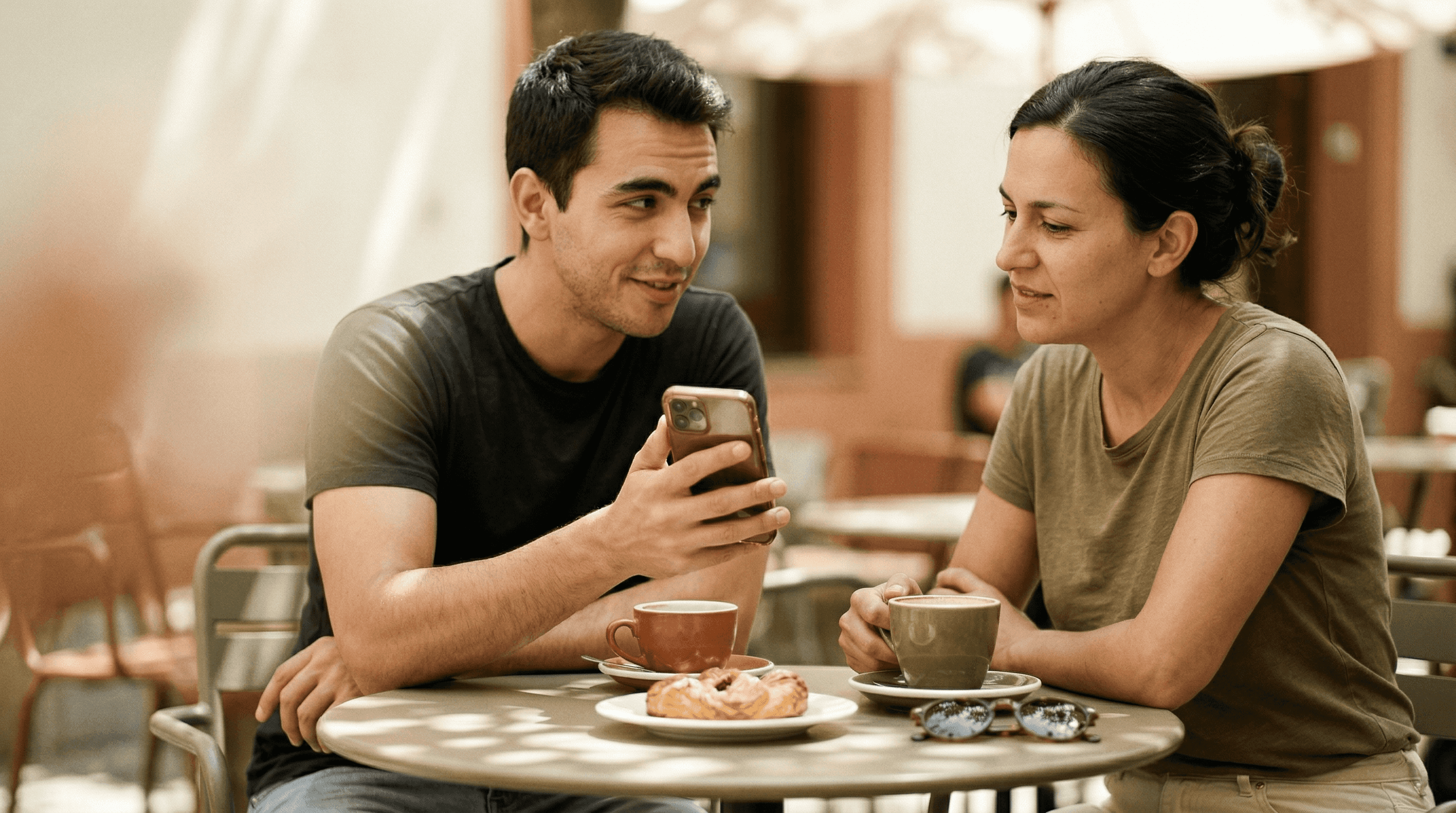 two people at a cafe looking at a phone